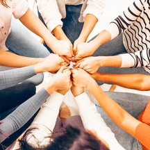 [Alt-text]: a group of people placing hands together in a circle